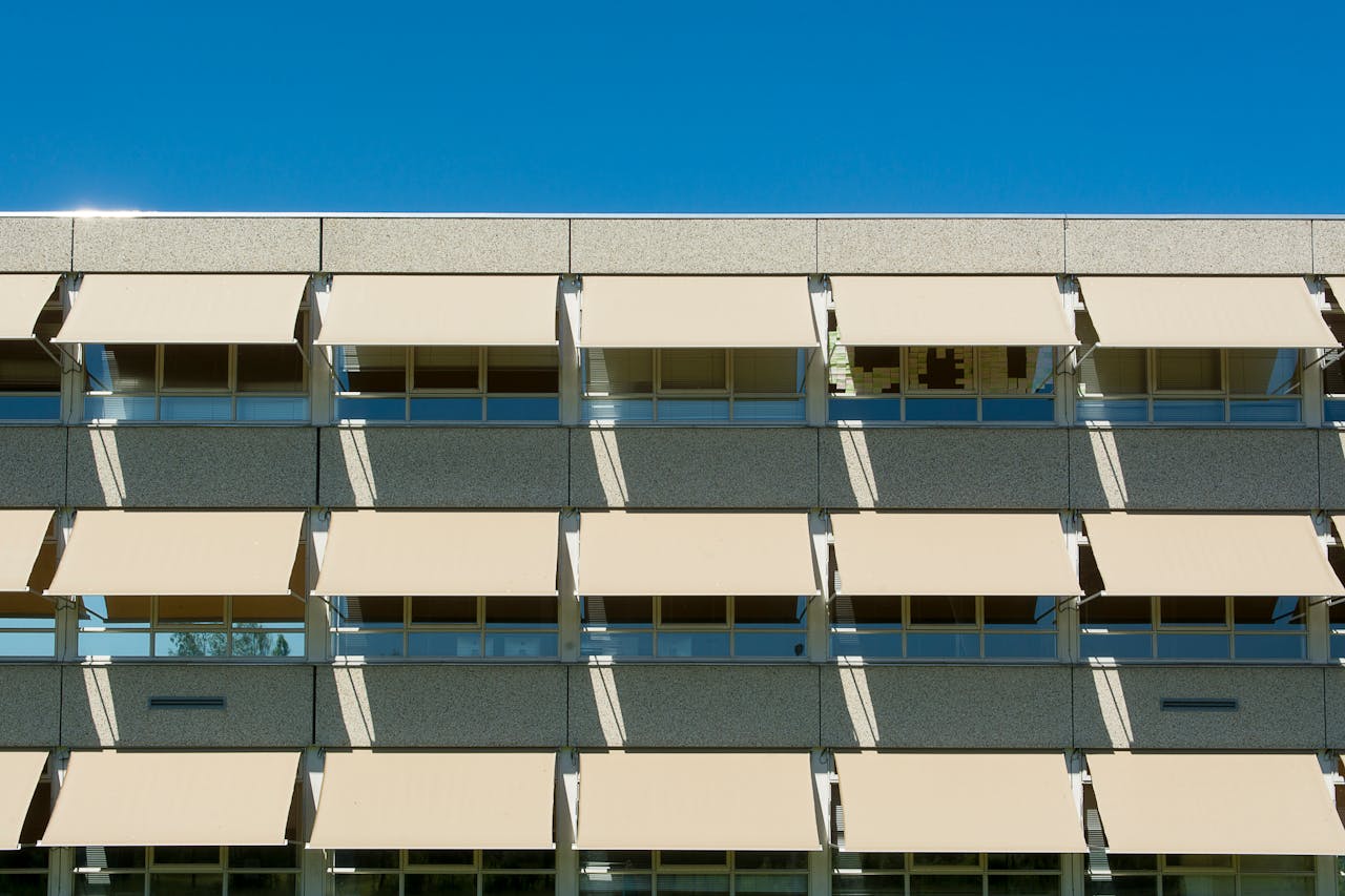 Facade of a modern residential building with sun shades under a clear blue sky.